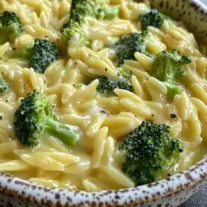 Creamy broccoli cheddar orzo dish served in a bowl, garnished with fresh herbs.