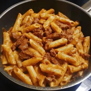 Creamy Sweet Spicy Beef Pasta dish garnished with herbs.