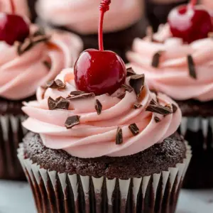 Decadent cherry chocolate cupcakes topped with creamy frosting and cherries.